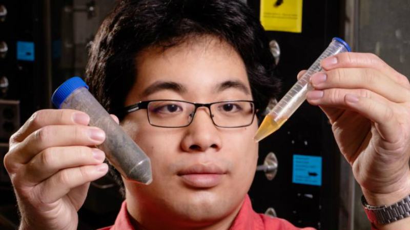 Mechanical science and engineering graduate student Timothy Lee holds a sample of waste and a sample of distillate the team derived from that waste (Credit: L. Brian Stauffer)