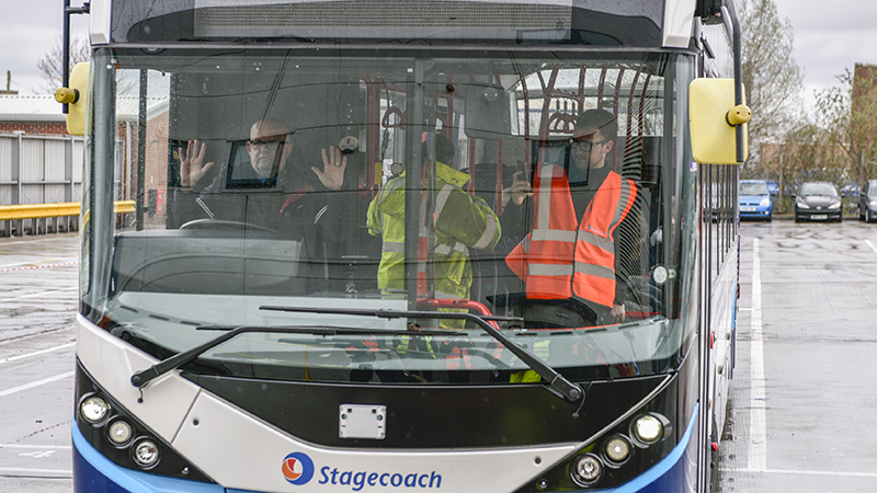 A driver raises his hands while behind the wheel of the bus (Credit: Alexander Dennis)