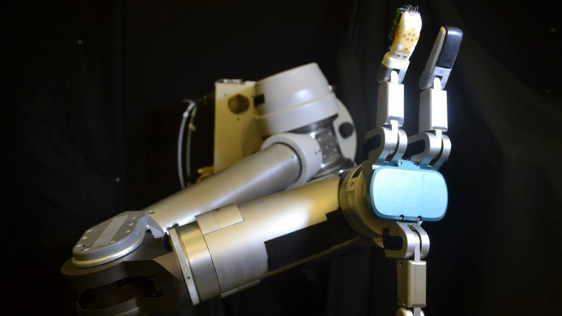 The flexible sensor skin wrapped around the robot finger (orange) is the first to measure shear forces with similar sensitivity as a human hand, which is critical for gripping and manipulating objects. (Credit: UCLA Engineering) 