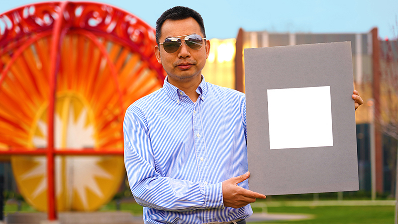 Xiulin Ruan, a Purdue University professor of mechanical engineering, holds up his lab’s sample of the whitest paint on record (Credit: Purdue University/ Jared Pike)